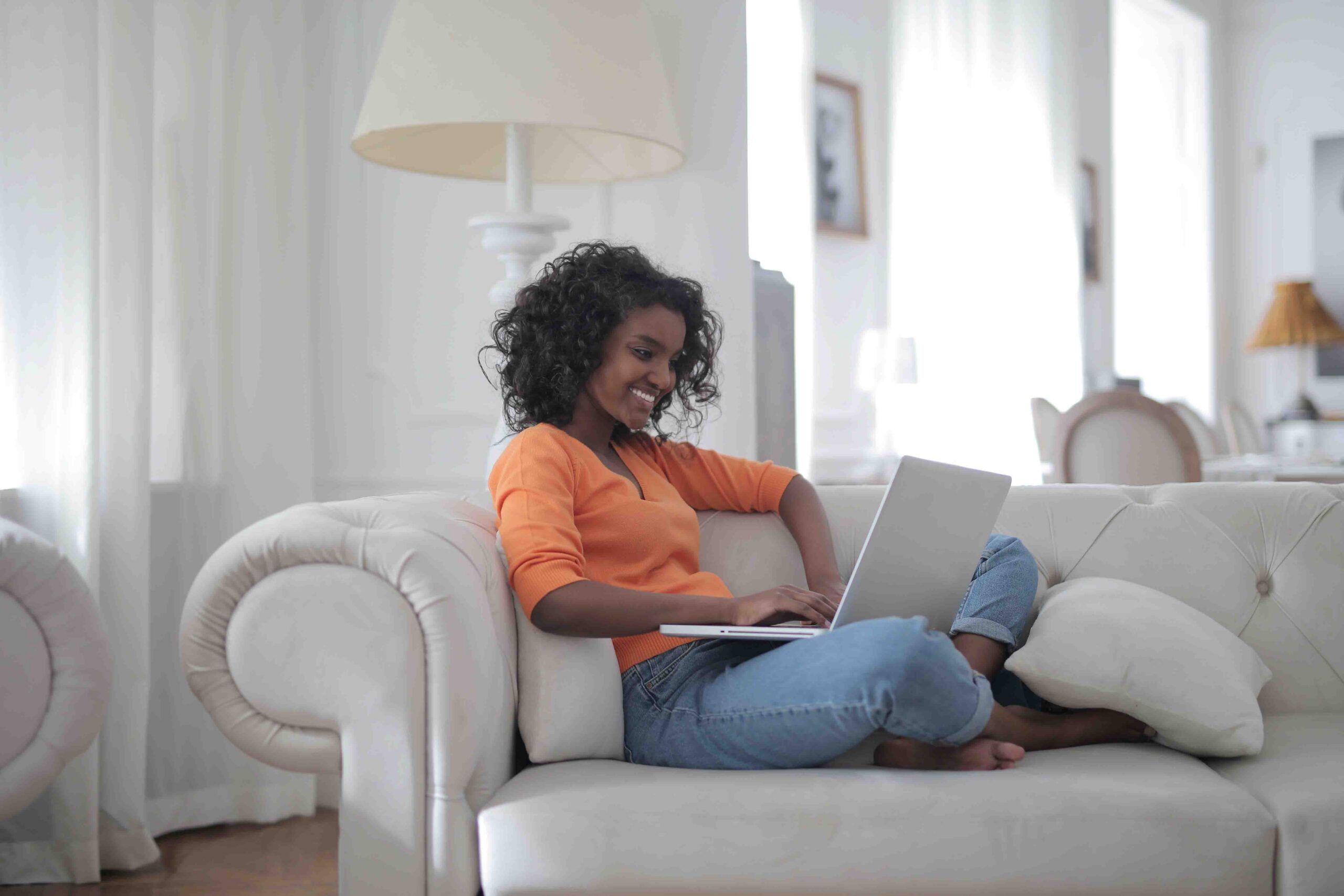 woman-sitting-on-white-couch-using-laptop